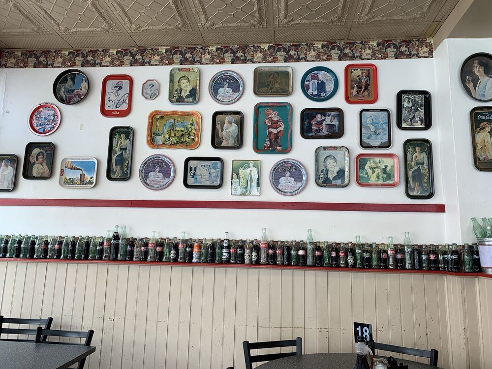 A wall of vintage Coca-Cola trays and bottles